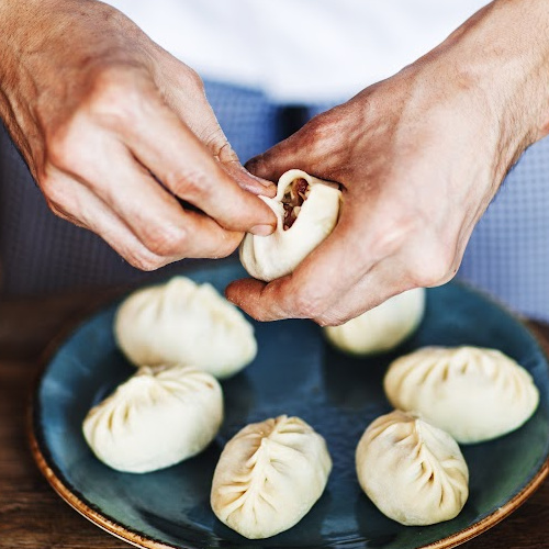 Two hands wrapping Chinese dumplings